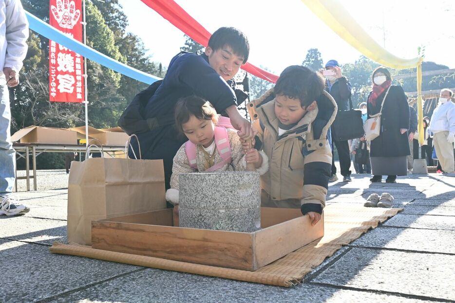 ソバの石臼びきを体験する参拝者