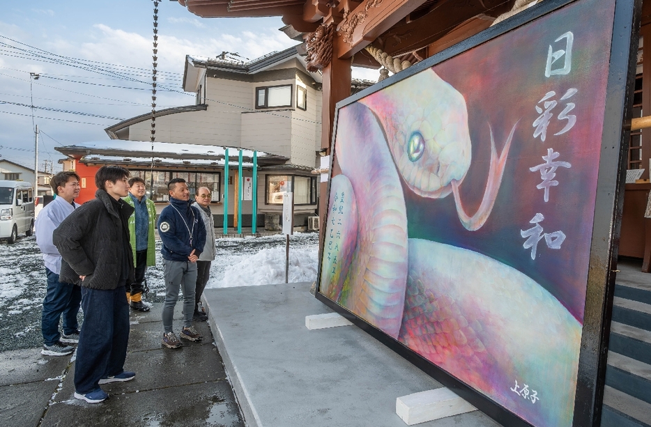 大絵馬の完成を喜ぶ、制作者の上原子創太さん（左から2人目）ら関係者＝26日、八戸市