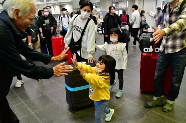 出迎えた祖父母らに駆け寄ってハイタッチする女の子＝28日、宮古空港