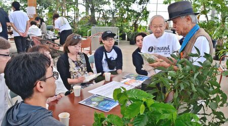 コーヒーとカラキの葉で作る「珈茶唐（コティカラ）」について説明する名城政雄さん（右）と参加者＝１１月２３日、名護市のなごアグリパーク