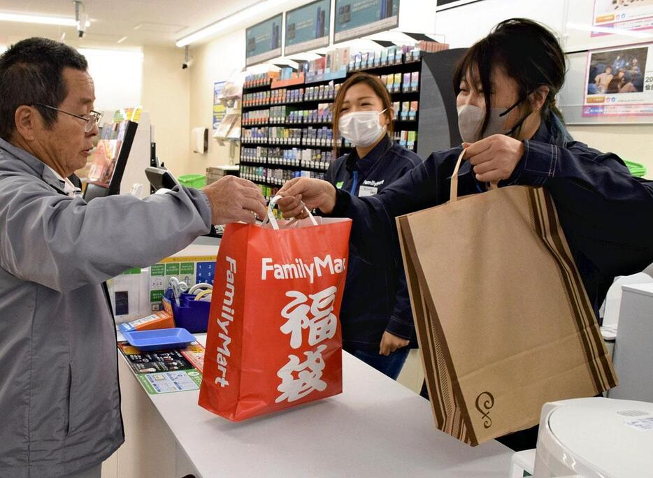 開店記念の福袋などを購入する買い物客（左）＝大熊町