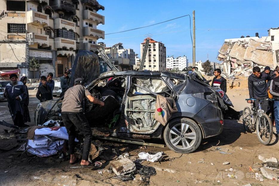 パレスチナ自治区ガザ市中心部のジャラ通りで、イスラエルの爆撃を受けた民間車両の残骸の周りに集まる人々（2024年12月22日撮影）。【翻訳編集】 AFPBB News