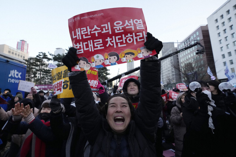 韓国国会前で、尹錫悦大統領の弾劾訴追案可決を喜ぶ人々。プラカードには「内乱の首謀者、尹錫悦を処罰せよ」と書かれている＝ソウルで2024年12月14日、AP