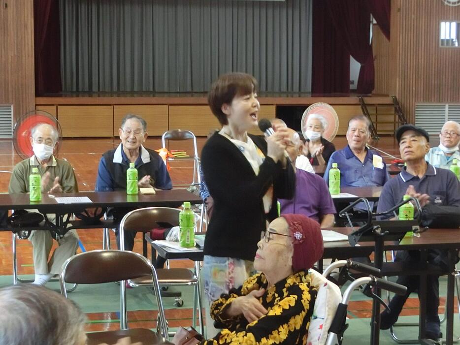 孫のまさえさんのカラオケをうっとりと聴く仲田幸子さん（中央手前）＝11月12日、宜野湾市我如古公民館