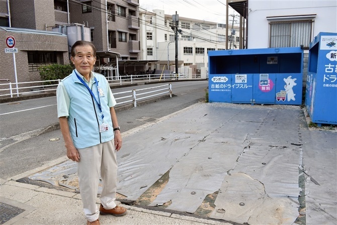 小学校近くの古紙回収スペースに立つ田中秀次さん。相談を受け、登校時間の出入り中止を実現した