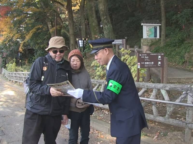 登山者に安全な登山を呼びかける警察官＝２５日、岐阜市、岐阜公園