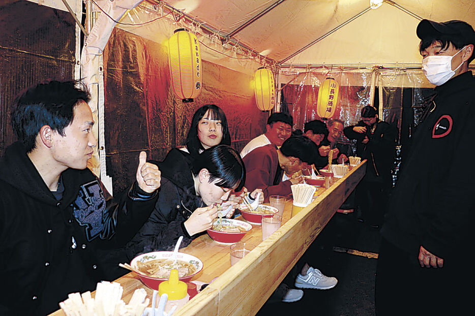 屋台風の店舗でラーメンを味わう利用客＝小松市三日市町