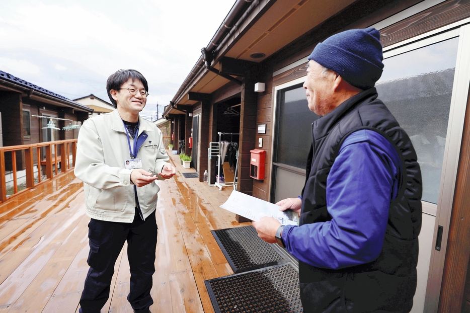 仮設住宅に入居する被災者に広報紙を届ける藤沢さん（左）（27日、石川県珠洲市で）＝須藤菜々子撮影