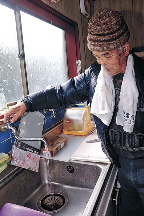 台所の水が出ることを確認して喜ぶ住民＝２５日午前１１時半、珠洲市片岩町