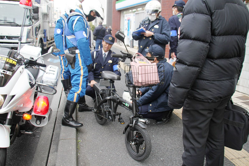 ペダル付き原動機付自転車の整備状況を調べる警察官ら＝13日、川口市西川口3丁目（画像の一部を加工しています）