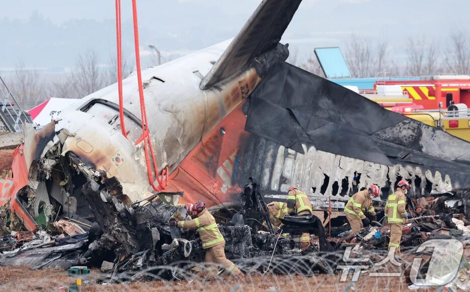 30日午前、務安国際空港で事故機の残骸を捜索する消防隊員(c)news1