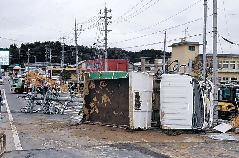 横転したダンプカーと倒れて道路をふさいだ電柱＝珠洲市飯田町