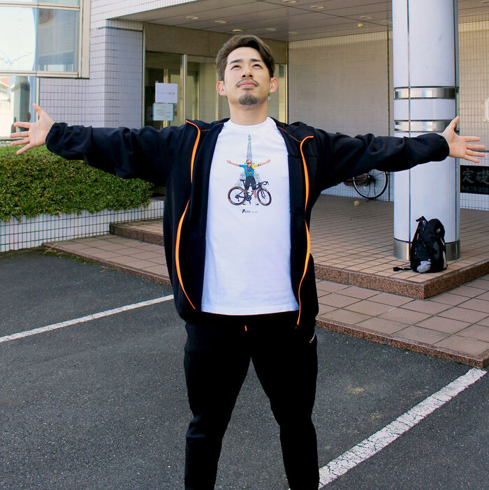 パリ五輪自転車ロードレース金メダリストのレムコ・エヴェネプール（ベルギー）のＴシャツと同じポーズを決める新山