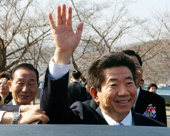 韓国の盧武鉉（ノ・ムヒョン）元大統領は２００４年３月１２日、大統領に対する国会の弾劾案が可決された日、慶尚南道鎮海（キョンサンナムド・チンヘ）の海軍士官学校で第５８期卒業式行事に参加するなど日程を継続していたところだった。写真は卒業式を終えた後、手をあげて挨拶して行事場所を離れようとしている盧元大統領。［中央フォト］