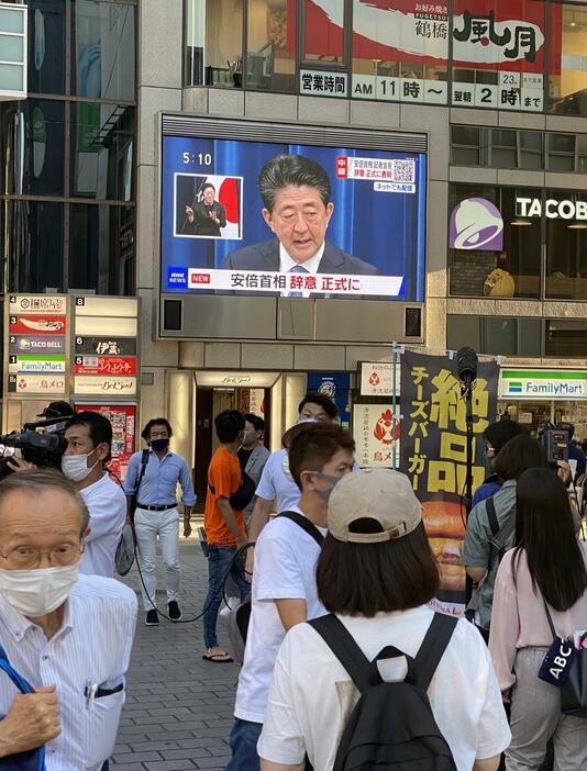 ［写真］生中継された会見の様子を見守る人たち＝28日午後5時10分ごろ、大阪市中央区で