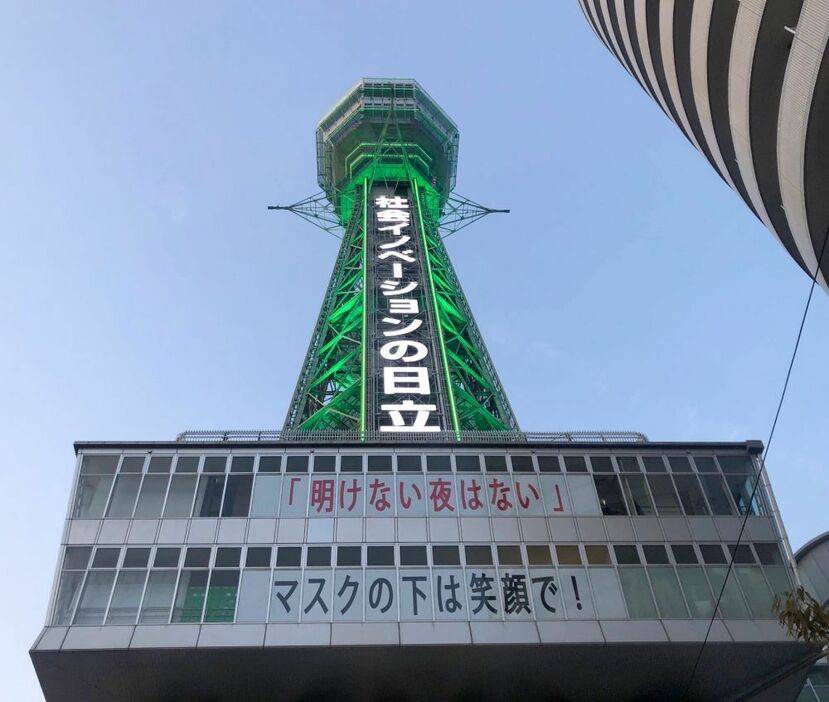 ［写真］通天閣の大窓には「明けない夜はない」「マスクの下は笑顔で！」という高井社長のメッセージもはられている＝14日午後7時ごろ、大阪市浪速区で