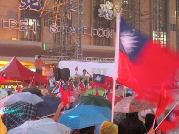 [写真]台北駅前に集まる台湾国旗を手にした人々