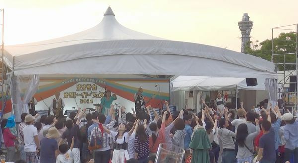 [写真]通天閣やあべのハルカスを眺めながらビール片手に音楽や踊りを楽しむ来園者ら（大阪市天王寺区で）