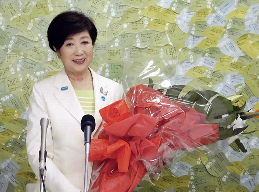 支援者から寄せられた花束を手に笑顔の小池知事