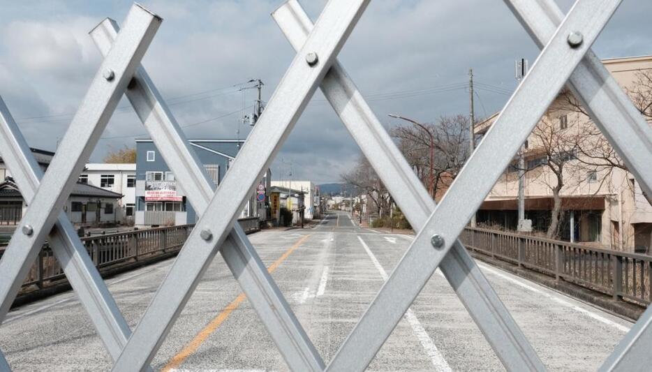 6号線の柵から望む双葉町の通り。かつて有名なスローガン「原子力　明るい未来のエネルギー」という看板があった。すべてが取り去られたいま、町は以前にも増して寂しげに見える。多くの人たちで賑わっていた町には誰もいない。そして人々が戻る日が来るのかどうか、それさえもわからない　　双葉町（撮影：村田信一）