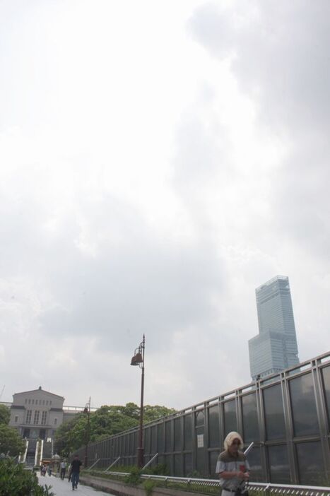 [写真]梅雨明けで曇天模様の大阪市内、時折雲のすき間から強い日差しも。右はあべのハルカス＝21日午前、大阪市天王寺区の大阪市立美術館前で