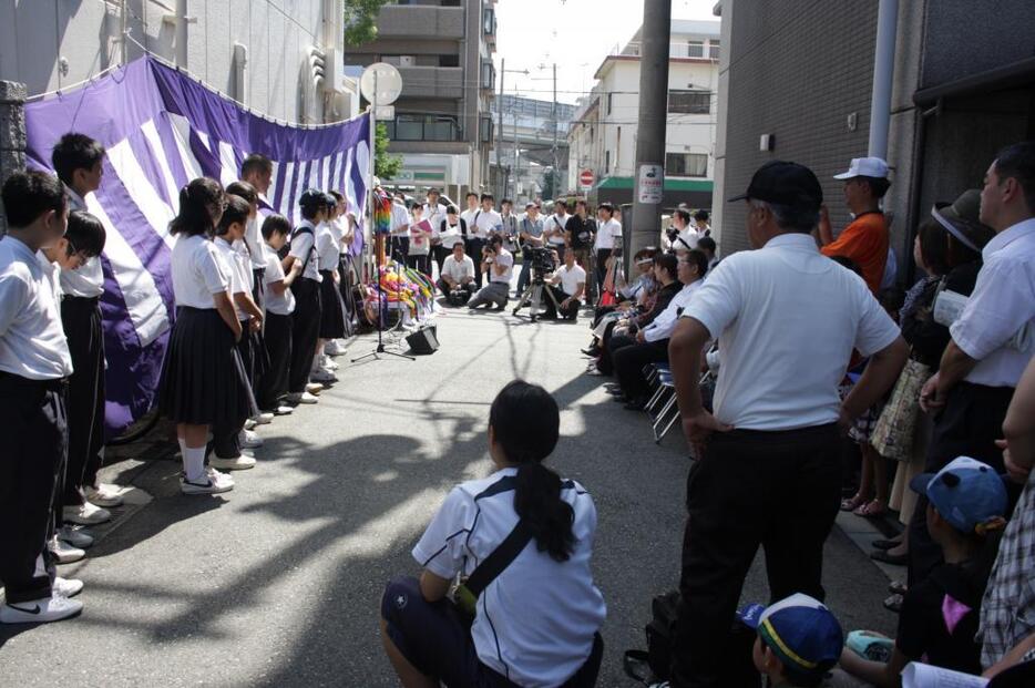 [写真]年々参列者は増えている。奥左側のマンション付近に爆弾が投下されたという=26日午前、大阪市東住吉区で