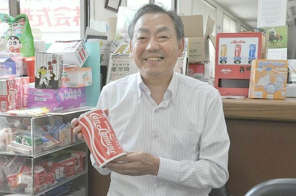 [写真]ロングセラー「ミニコーラ」のジャンボサイズを持つ高岡五郎さん。かつて子どもたちにとって、コーラは大人が飲む憧れの味だった